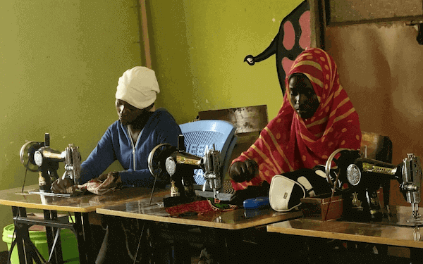 2 Tanzanian women sewing at treadle sewing machines