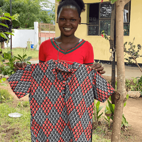 Smiling Tanzanian woman holding brightly coloured shirt